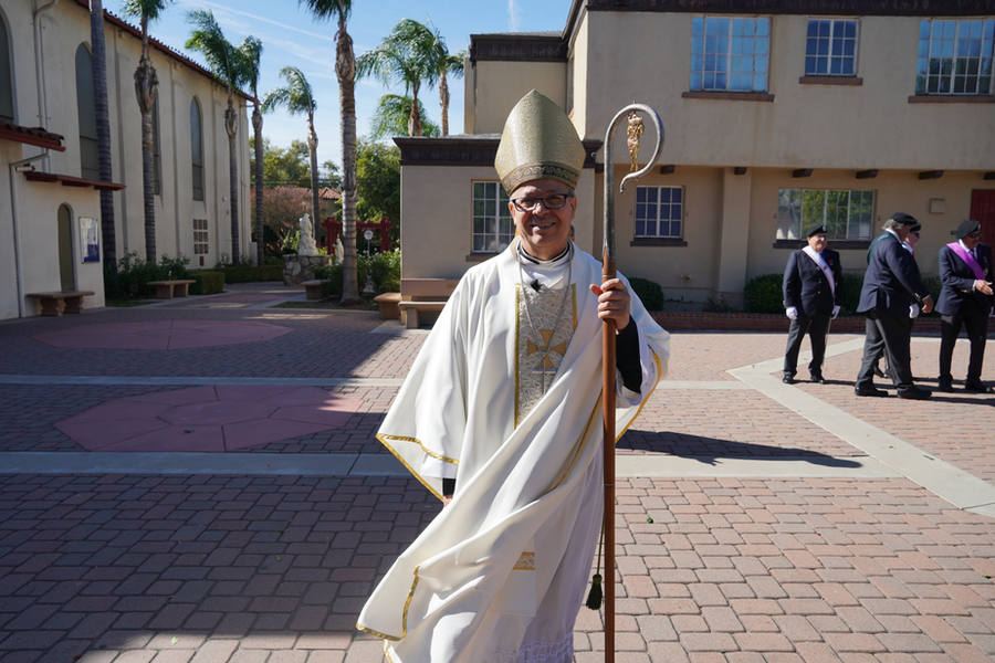 A bishop holding a crozier outside a church