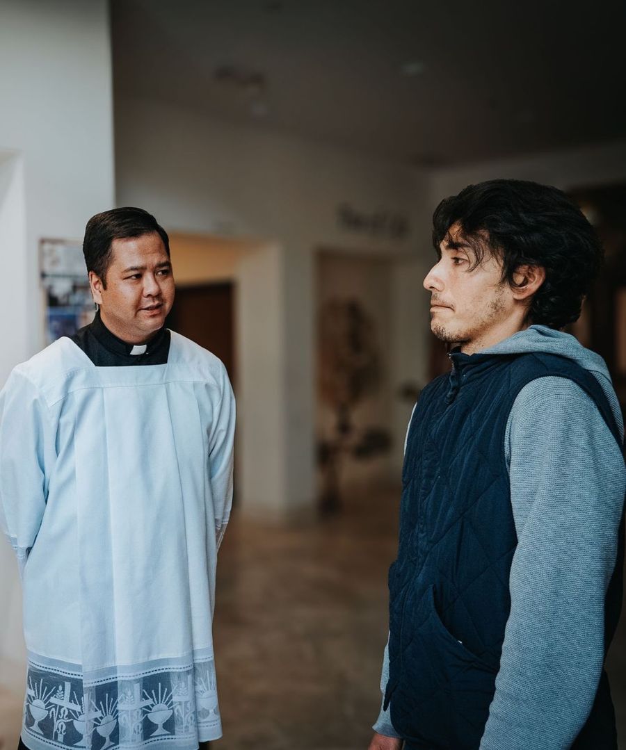 A priest talking with a young man at Serra House