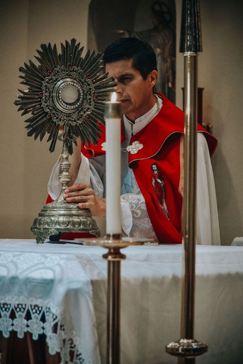 A priest in red vestments beside the monstrance during adoration