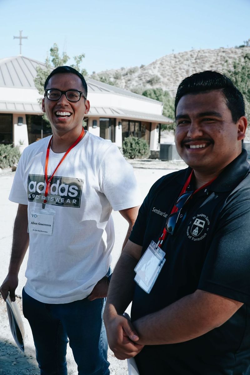 Two smiling volunteers with lanyards outside Serra House